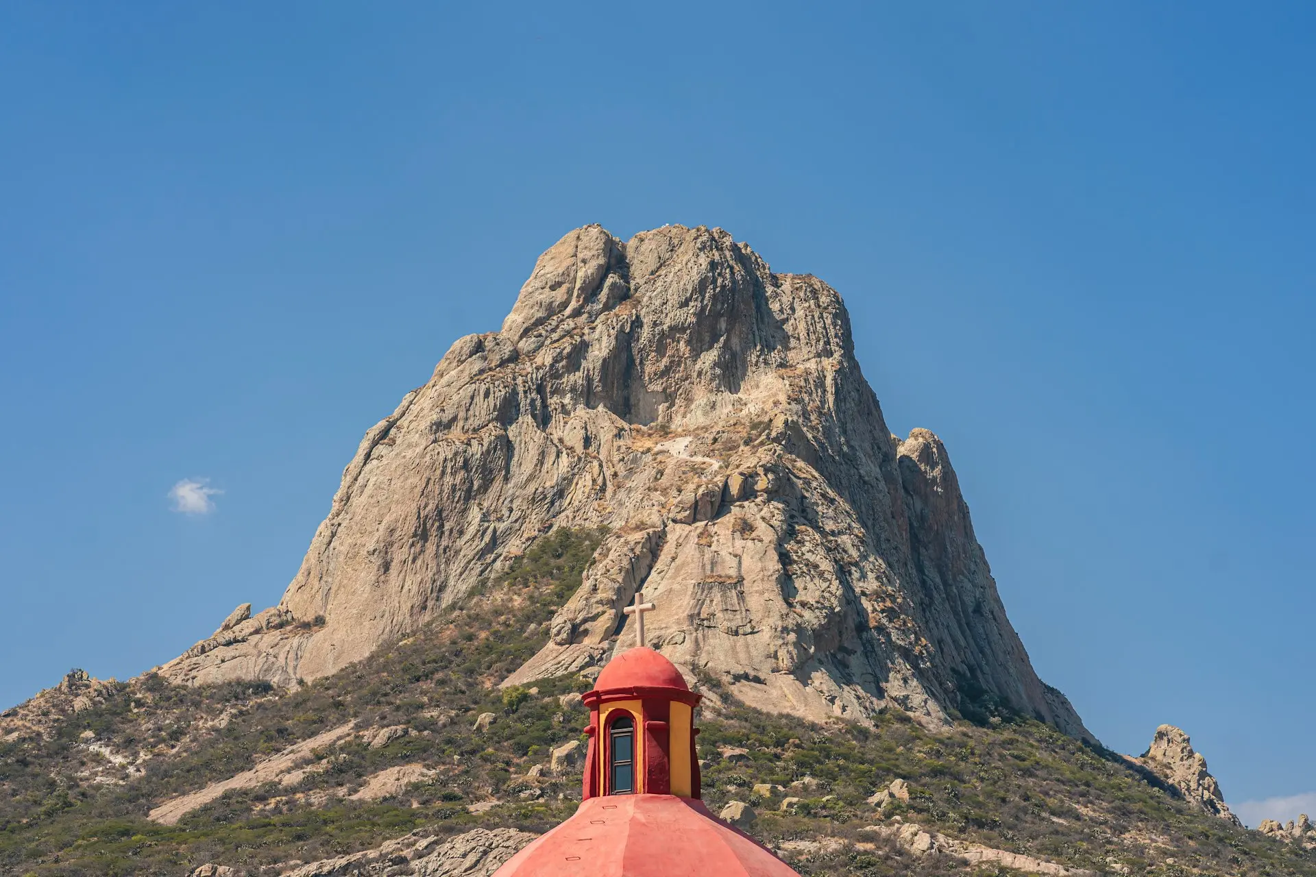 a red dome on top of a building in front of a mountain