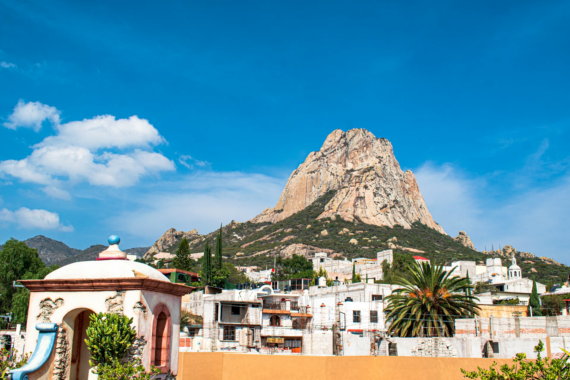 white and brown concrete buildings near green mountain under blue sky during daytime